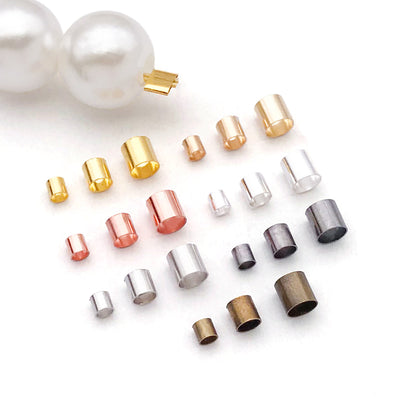 Metallic crimp bead jewelry findings arranged on a light background