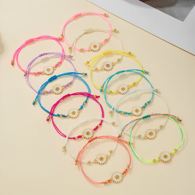 Twelve multicolor daisy cord bracelets scattered on beige surface