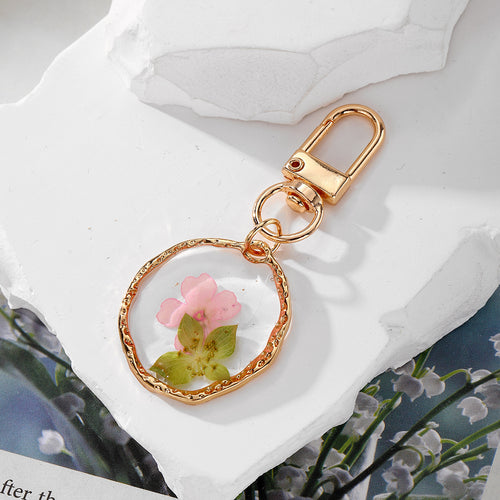 Close-up showing the colors and surface details of gold Tone Geometric Pressed Flower Resin Clip Keychains