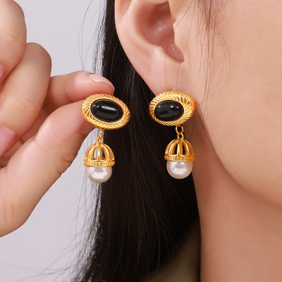 Gold black agate oval stud with pearl cage drop earring worn and held
