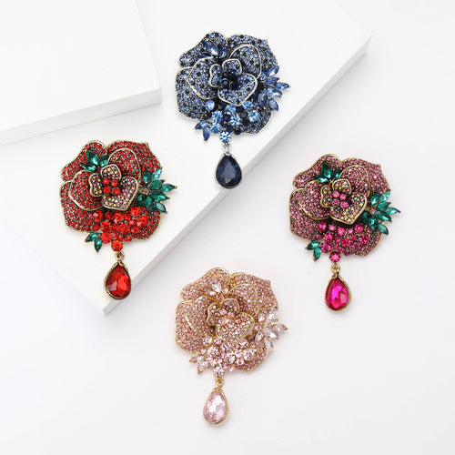 Four peony brooches red blue pink magenta on white platforms