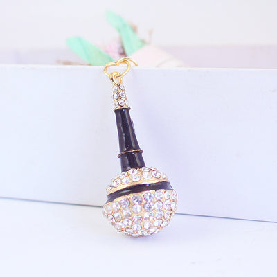 Close-up of a black microphone ornament with clear rhinestones hanging from a small ring.