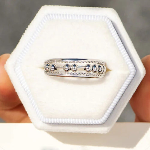 Silver abacus bead ring in hexagonal white jewelry tray held by hands