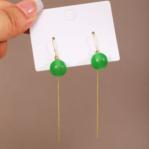 Green bead gold threader earrings on white card held by hand