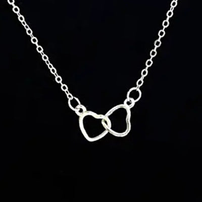 Silver interlocking open heart pendant necklace close-up on black background