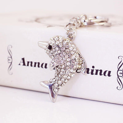Close-up of a clear rhinestone dolphin charm attached to silver tone key hardware.