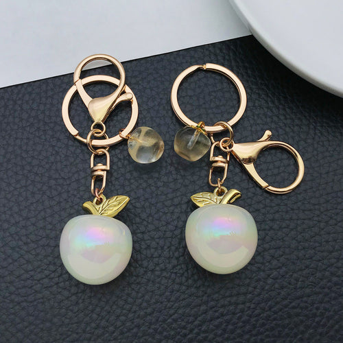Styled close-up of six-color iridescent apple double ring keychain showing colors and surface details