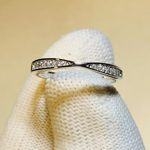 Twisted pave clear band held by white glove fingertip