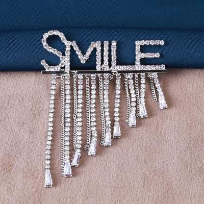 Front view of a crystal SMILE word brooch with long graduated fringe