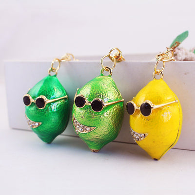Three textured lemon keychains in dark green, light green, and yellow sit side by side.
