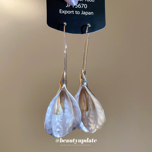 iridescent shell petal drop earrings with gold tone hooks shown in an on-ear styling view