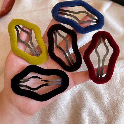 Five velvet irregular duckbill clips in mustard brown navy burgundy black held in hand