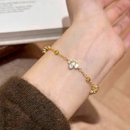 Gold CZ flower bracelet worn on wrist with brown sweater sleeve