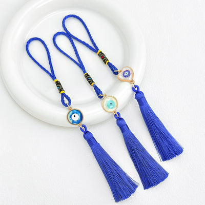 Three evil eye tassel charms in round and heart-shaped eye designs shown together