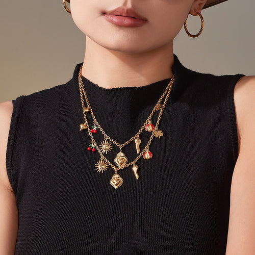 Model wearing layered gold multi-charm necklaces on black top