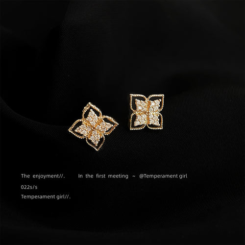 Mini gold four-petal floral pave studs on black fabric
