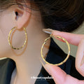 Gold Tone Twisted Oval Hoop Earrings with Detailed Finish view 1