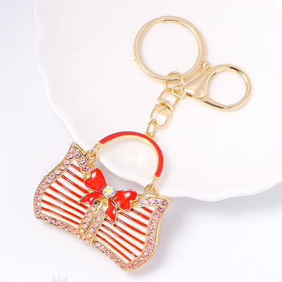 Red striped handbag keychain with bow on white dish