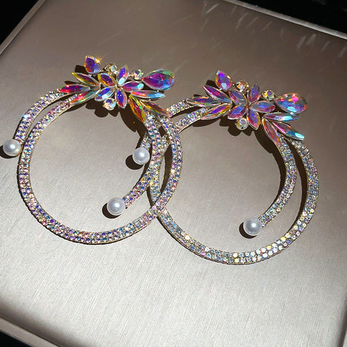 Large silver-tone hoops topped with multicolor leaf-shaped crystals shown in a styled view.