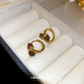 Gold Tone Twisted Hoop Earrings With Faceted Brown Square Stones view 1