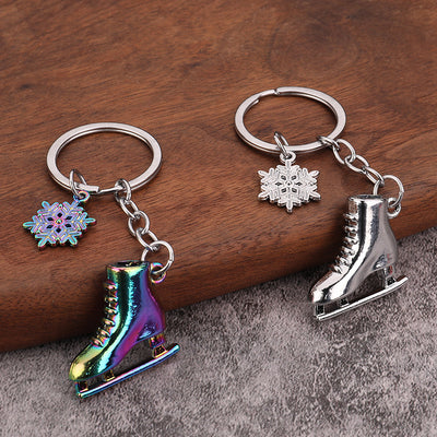Silver and iridescent ice skate keychains displayed together on wood and fabric.