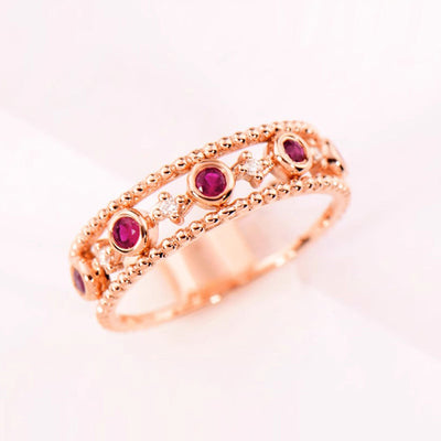 Rose gold beaded openwork ring magenta stones angled on white background