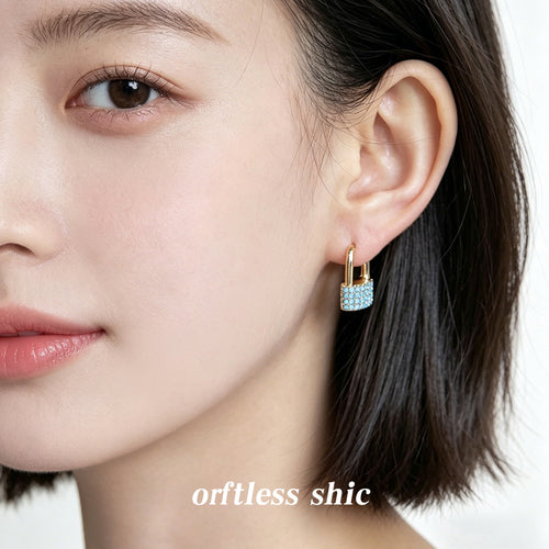 Gold-tone aqua-clear-stone padlock huggies shown worn on an ear.