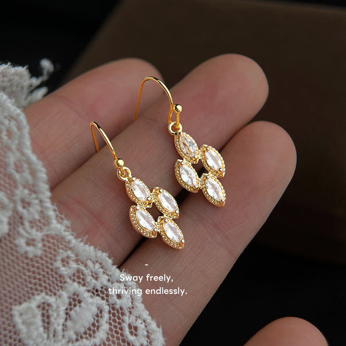 Gold marquise crystal cluster fishhook earrings held in open palm