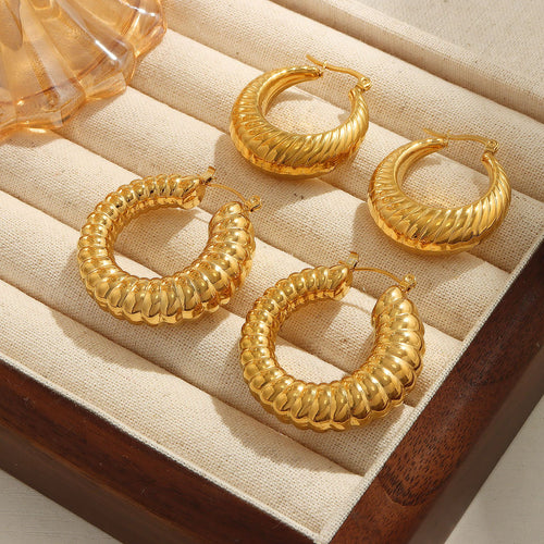Four gold twisted and ribbed hoop earrings in jewelry tray