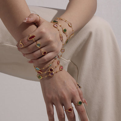 Arms stacked with multicolor gold Czech glass bezel bracelets and rings