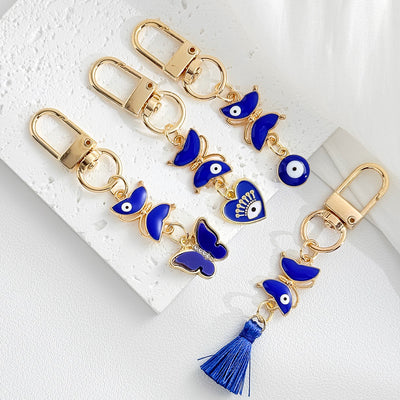 Blue evil eye tassel keychain shown clipped onto a bag strap