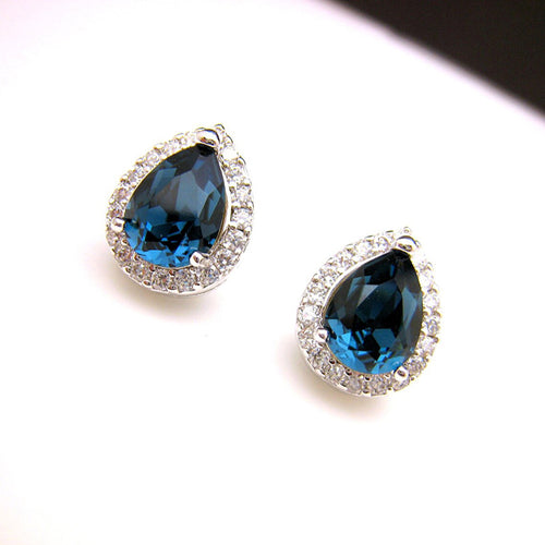 Pair of blue teardrop halo studs on white curved surface