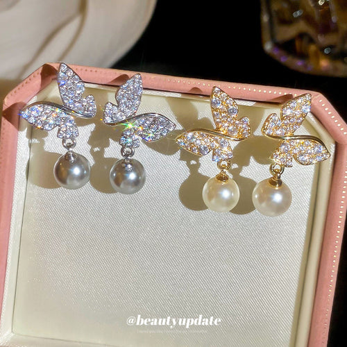 A styled close view of the butterfly pearl look drop earrings.