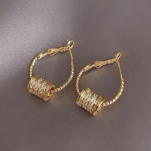 Slender twisted hoops carrying three crystal-set barrel accents shown in a styled front view.