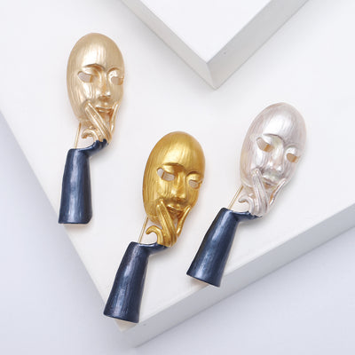 Product display showing a long sculptural face resting against a hand above a dark sleeve