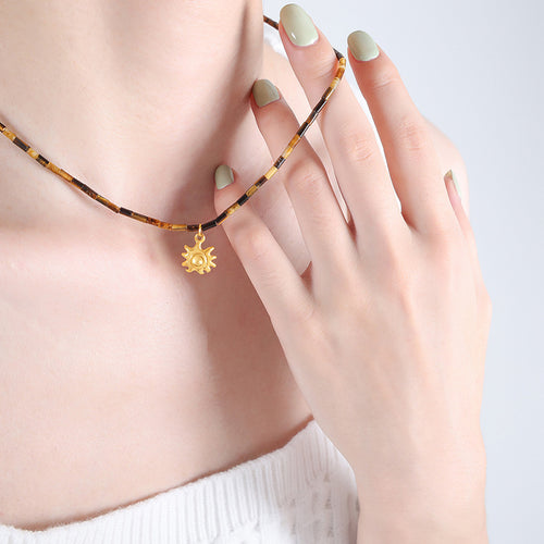 Tiger eye tube bead necklace with gold sun pendant worn close-up