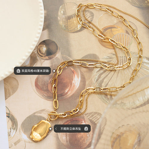 Flat lay gold dual chain irregular pendant among glassware
