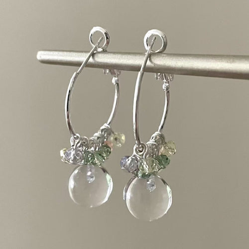Slender hoops carrying green, red and clear rounded drops shown in a styled view.