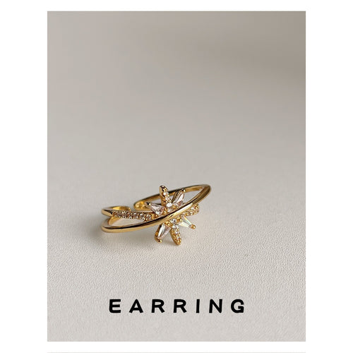 Gold-tone double-band clear-stone starburst open ring shown worn on a hand.