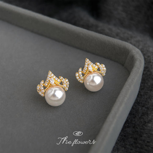 Gold crown pearl stud earrings on gray jewelry tray