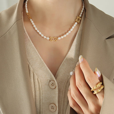 Freshwater pearl necklace with gold open stars worn on beige cardigan neckline
