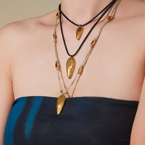Layered gold teardrop pendant necklaces worn on model chest