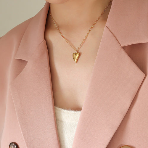 Model in pink blazer wearing gold smooth heart pendant necklace