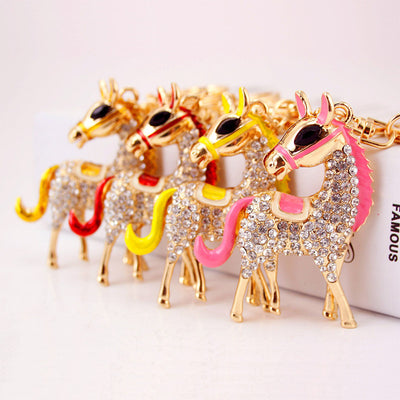 Four horse keychains with pink, yellow, red, and gold accents arranged in a row.