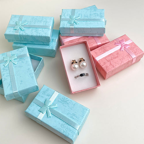 Blue and pink bow jewelry boxes stacked with open pink tray of props