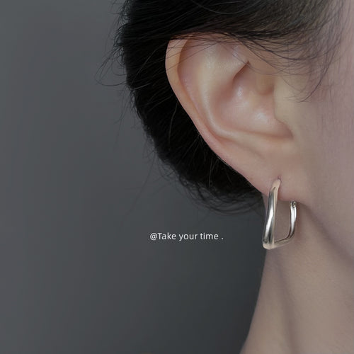 Silver-tone irregular open-round hoop earrings shown worn on an ear.
