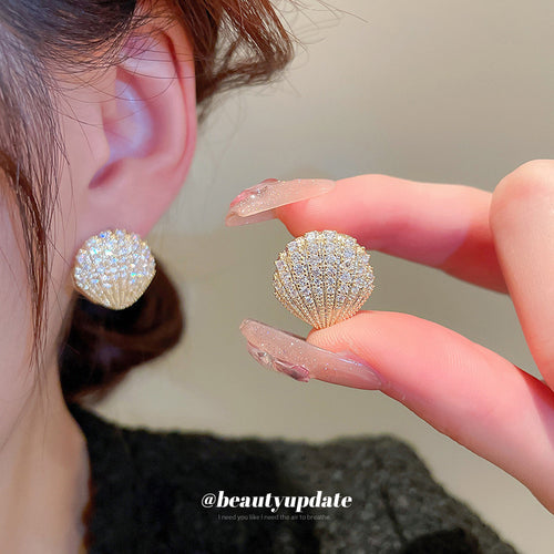 Product view of gold tone shell stud earrings with crystal pavé statement jewelry