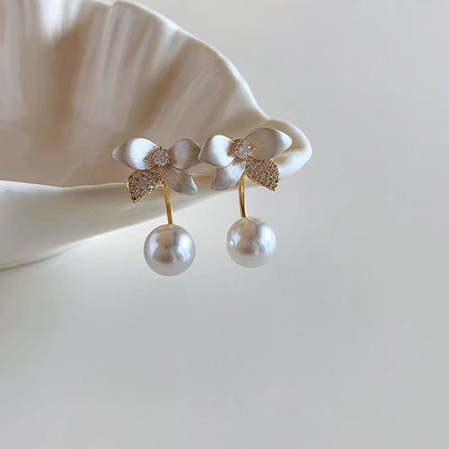 Primary view of white sculpted flowers with textured gold tone leaves and suspended round pearl-like drops