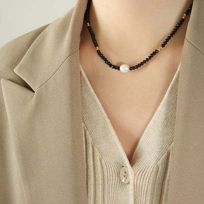 Black glass bead pearl center necklace worn with beige blazer and knit top