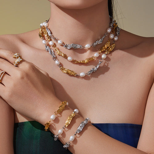 Model wearing layered gold steel two-tone pearl link necklaces and bracelets